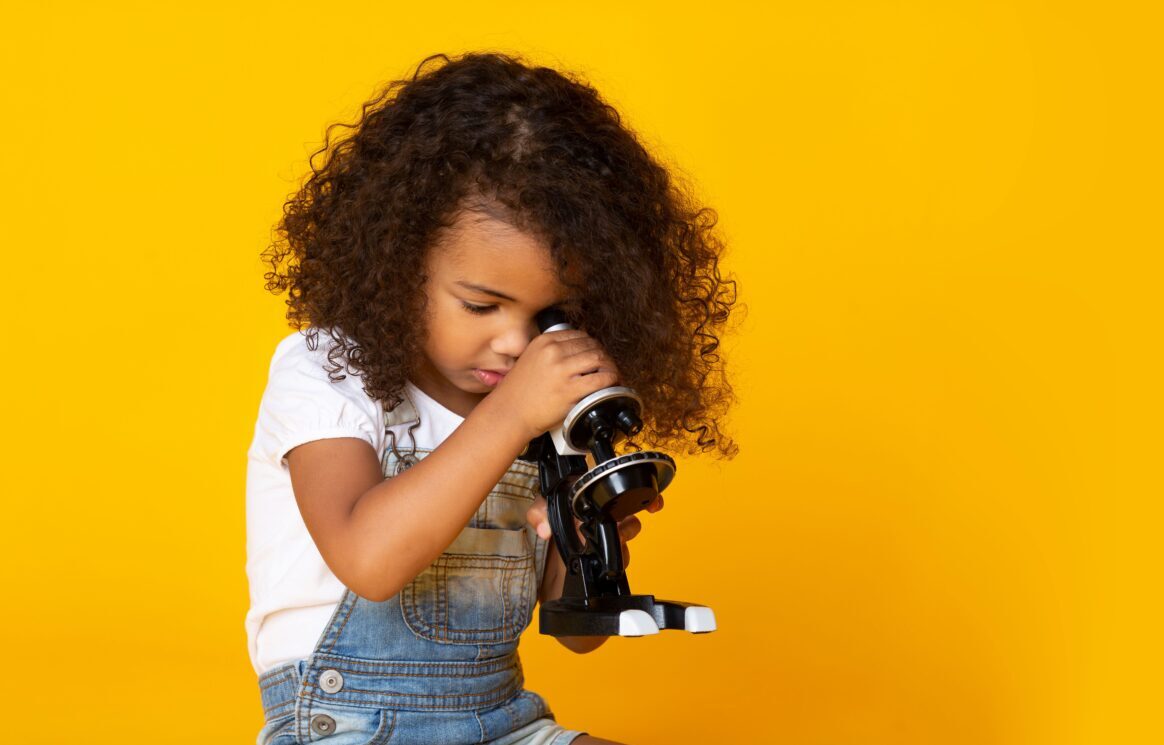 Mädchen schaut durch ein Mikroskop