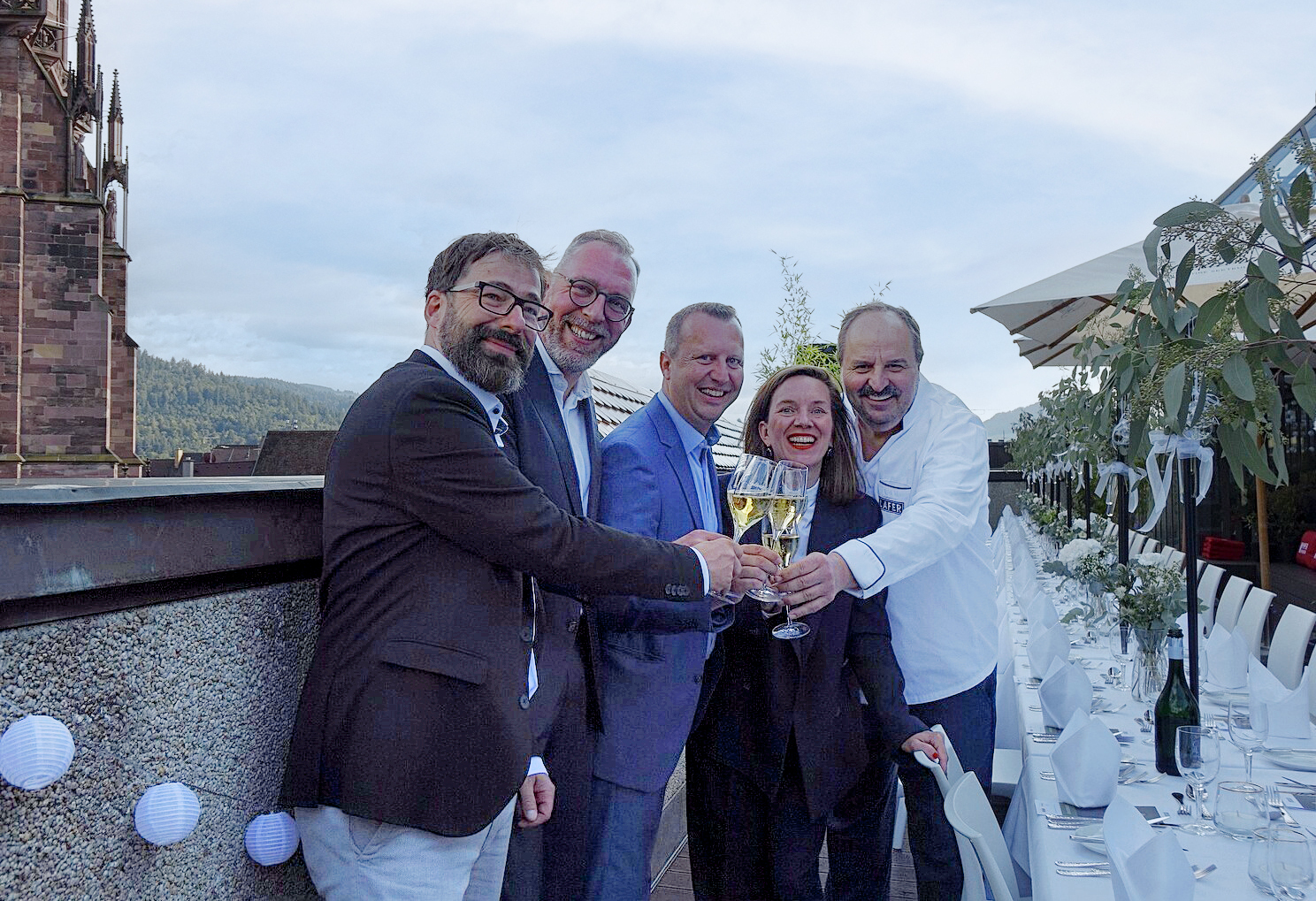 Stoßen auf ein schönes Sommer-Dinner auf der Breuninger Rooftop-Bar an: Jens Szabo (v.l.), Teamleiter der Breuninger-Confiserie, Matthias Schwarz, Abteilungsleiter Breuninger, Peter Lammer, F&B-Manager Breuninger, Hannah Oberbauer von Geldermann und Fernsehkoch Johann Lafer.